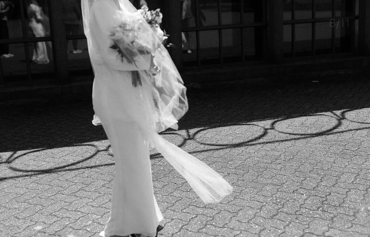 A bride crossing a courtyard with her bouquet, her veil caught mid-step.