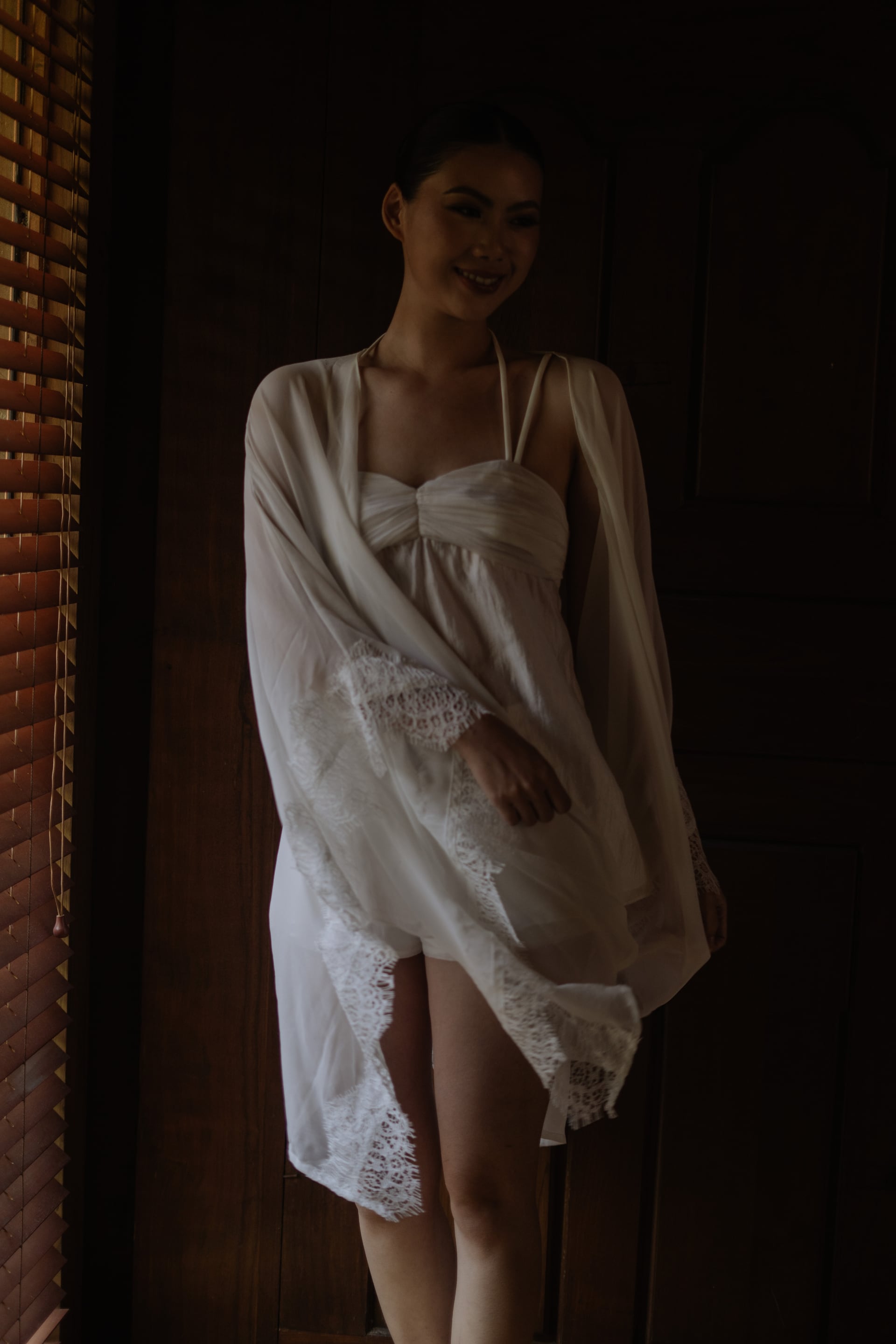 A bride in a lace-trimmed robe in a doorway before the ceremony.