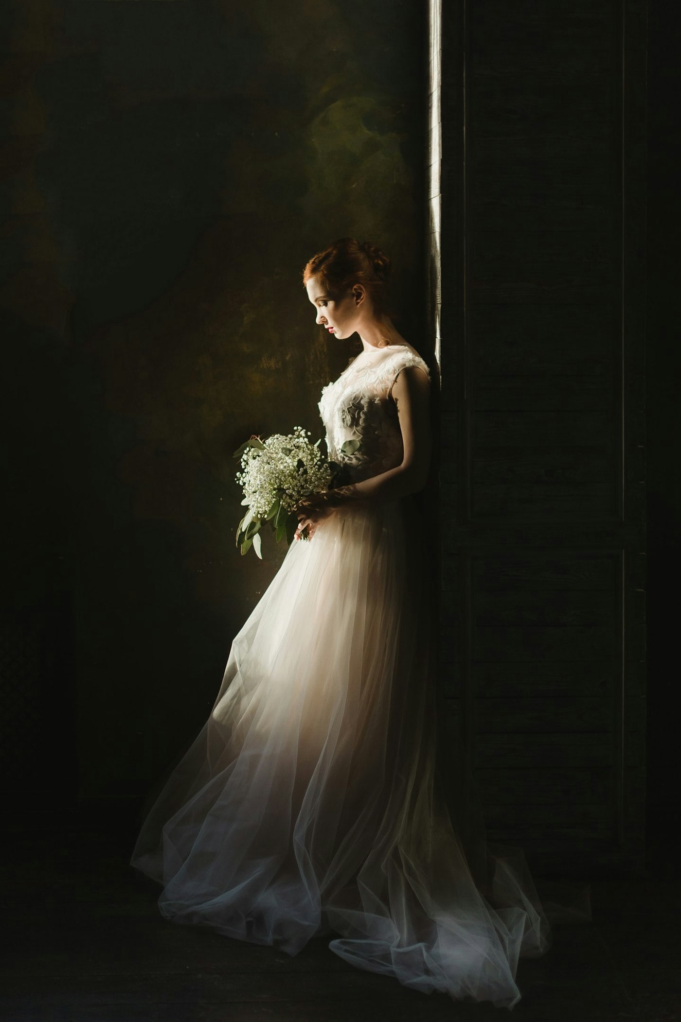 A bride standing in the light of an open doorway.